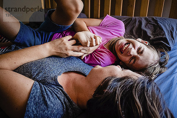 Hochwinkelansicht einer glücklichen Mutter mit Tochter  die zu Hause auf dem Bett liegt