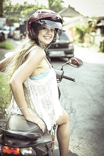 Porträt einer lächelnden Frau  die auf einem Motorroller sitzt