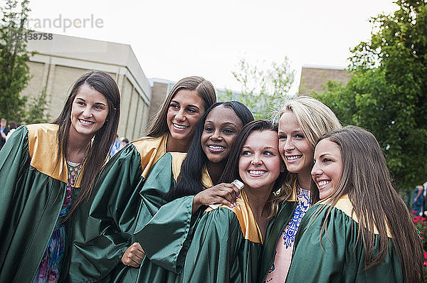 Glückliche Hochschulabsolventen-Freunde posieren auf dem Campus für Fotos