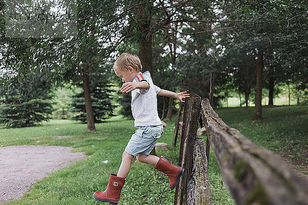 Junge springt in voller Länge vom Zaun im Park