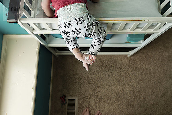 Niedriger Teil eines Jungen  der im Schlafzimmer auf das Etagenbett klettert