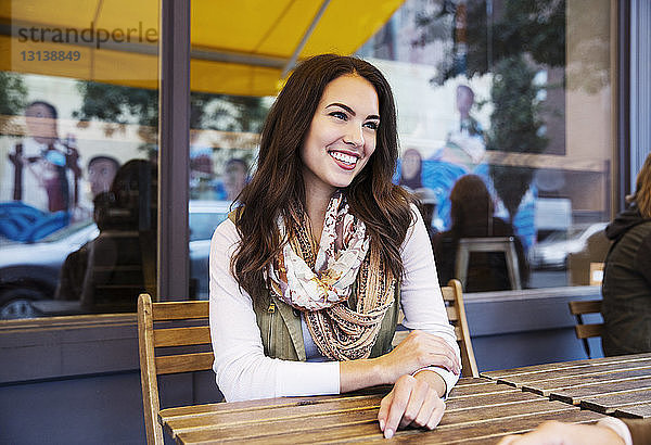 Glückliche Frau sitzt im Bürgersteig-Café