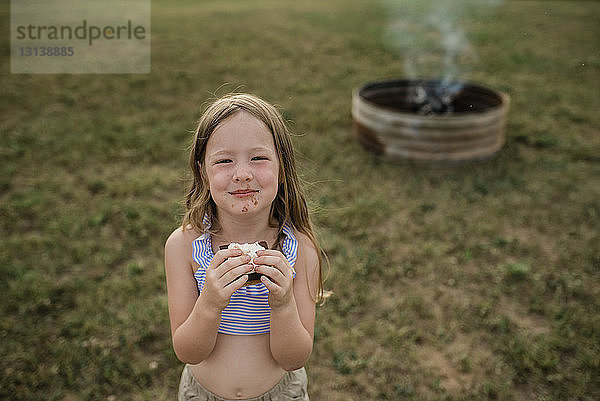 Porträt eines lächelnden Mädchens mit Smore im Hinterhof