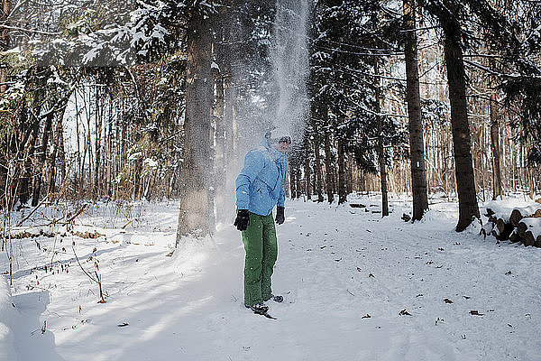 Mann steht auf schneebedecktem Feld im Wald