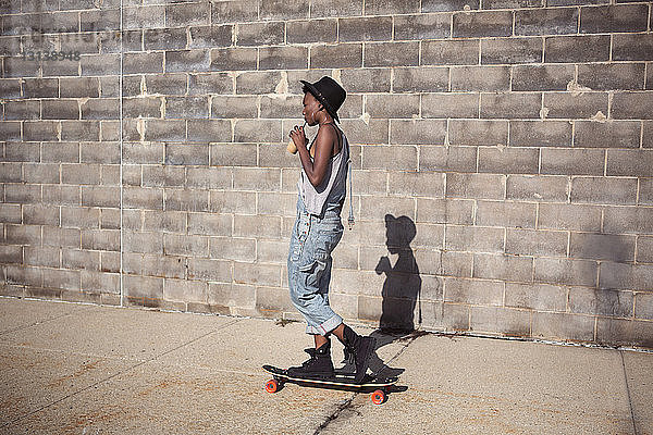 Seitenansicht einer Frau  die einen Smoothie trinkt  während sie auf einem Skateboard steht