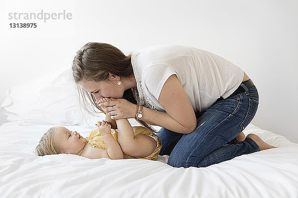 Seitenansicht der Mutter beim Spielen mit der Tochter zu Hause im Bett