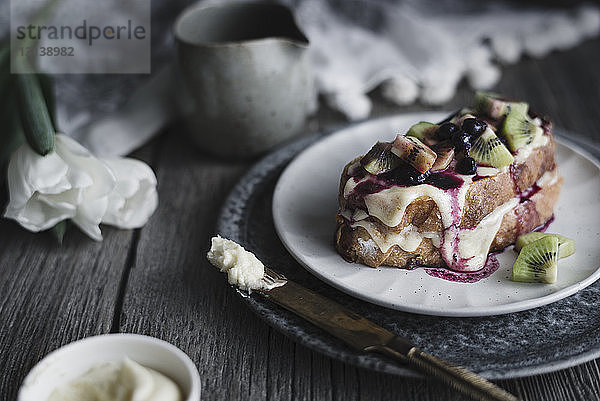 Nahaufnahme von French Toast mit Frischkäsebutter und Früchten im Teller auf dem Tisch