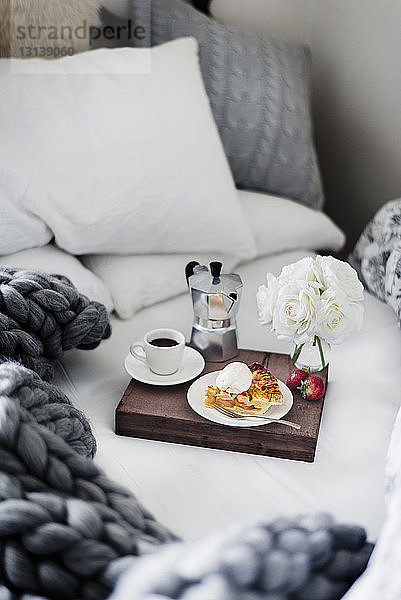 Apfelkuchen und Erdbeeren auf Holztablett im Bett