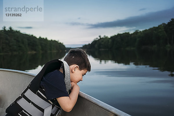 Seitenansicht eines Jungen  der eine Schwimmweste trägt  während er im Boot auf dem See sitzt