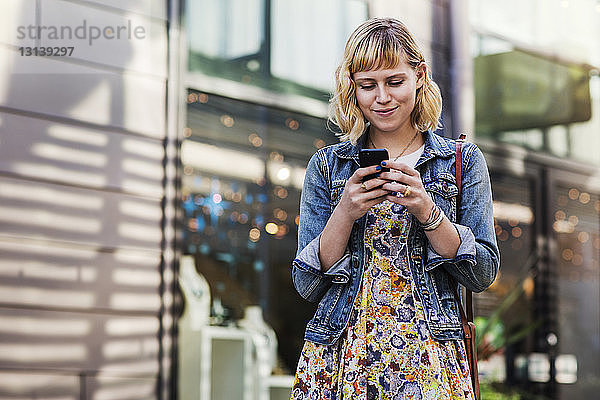 Frau benutzt Smartphone im Stehen