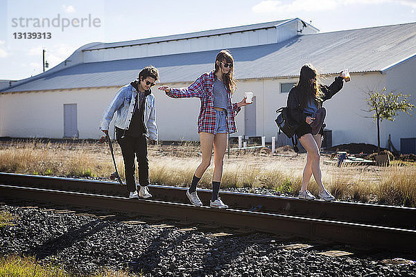 Spielerische Freunde gehen auf Eisenbahnschienen