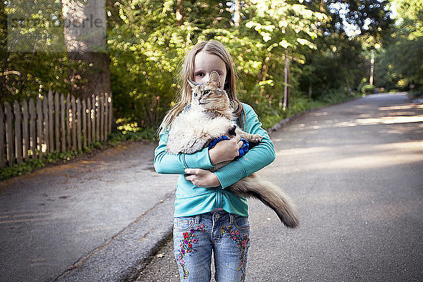 Mädchen trägt Katze  während sie auf der Straße steht