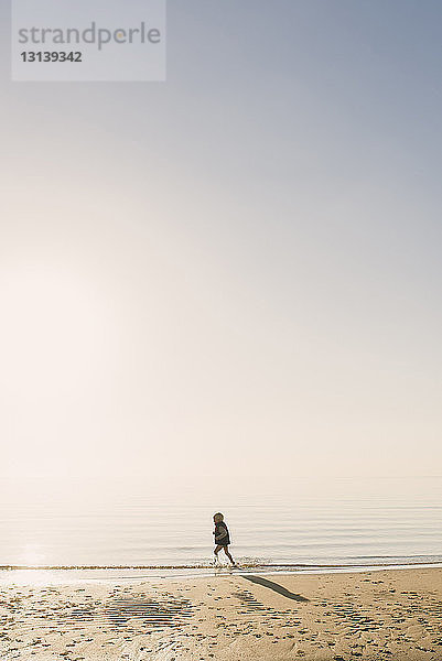 Seitenansicht eines Jungen mit Schwimmweste  der bei nebligem Wetter im Meer läuft