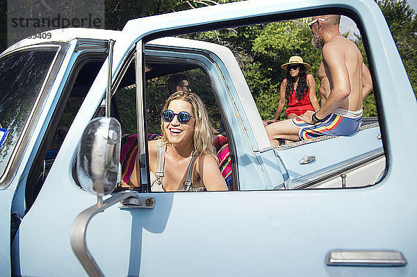 Glückliche Frau mit Sonnenbrille sitzt im Pick-up