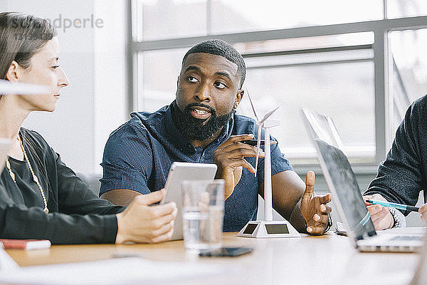 Geschäftsleute diskutieren über Windturbinenmodelle während einer Besprechung im Büro