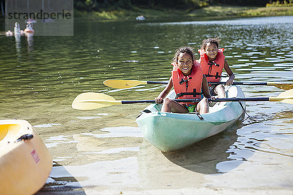 Porträt von Freunden mit Rudern in Schwimmwesten  die im Kanu auf dem See sitzen