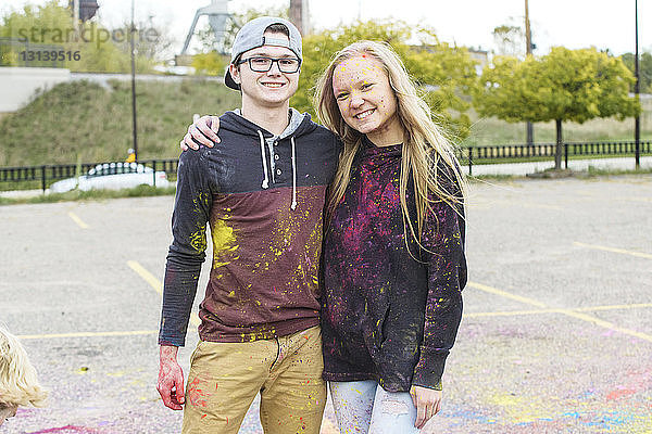 Porträt glücklicher Freunde mit Pulverfarbe auf Fußweg im Park stehend
