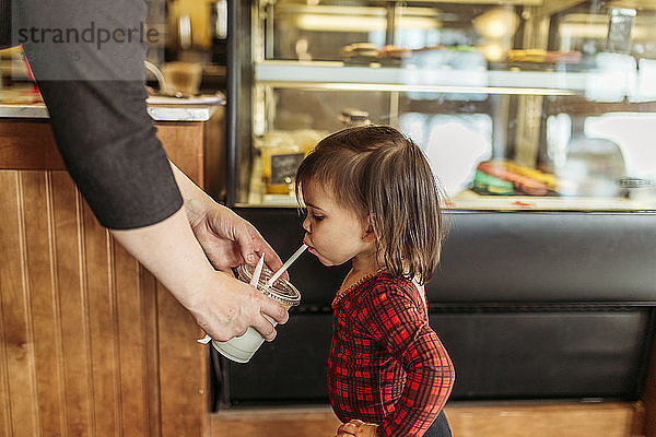 Mutter gibt im Restaurant Milch an Tochter ab