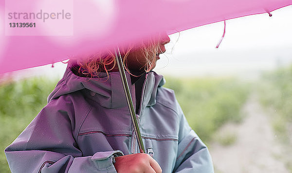 Mitschnitt eines Mädchens mit Regenschirm  das während der Regenzeit im Freien steht