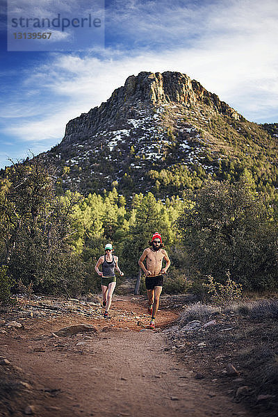 Entschlossenes Paar läuft auf Wanderweg durch Berg
