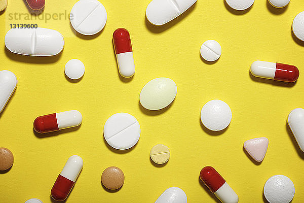 Hochwinkelansicht verschiedener Medikamente auf gelbem Hintergrund