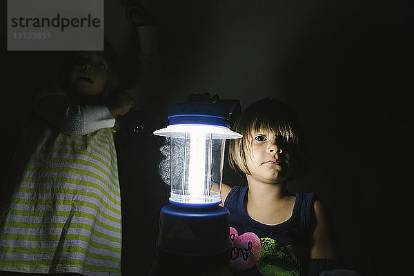 Porträt eines Mädchens mit beleuchteter elektrischer Lampe in der Dunkelkammer