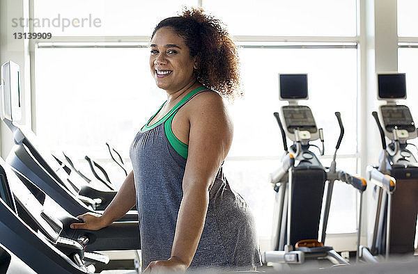 Porträt einer kurvenreichen Frau auf dem Laufband im Fitnessstudio