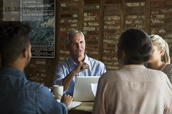 Zuversichtlicher Geschäftsmann im Gespräch mit Kollegen während eines Treffens im Café
