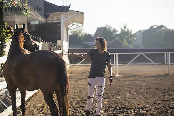Frau berührt Pferd mit Tierpflegeausrüstung  während sie auf der Ranch steht
