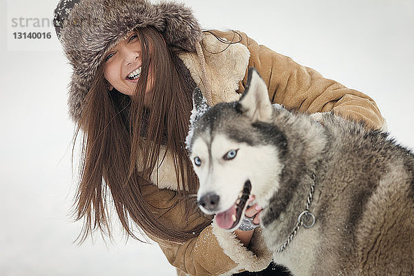 Porträt einer glücklichen Frau mit Siberian Husky im Winter