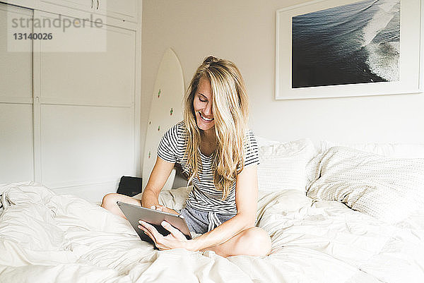 Glückliche Frau mit Laptop-Computer zu Hause im Bett