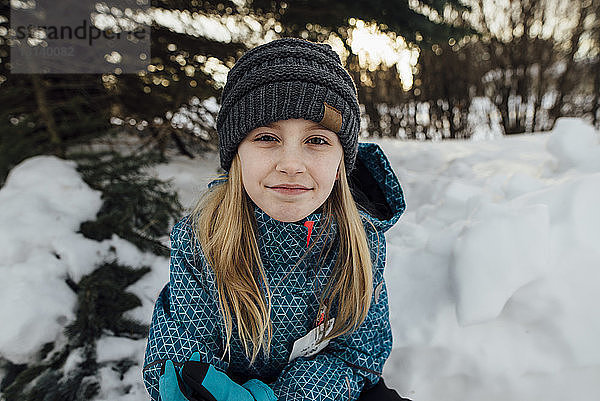 Porträt eines auf einem Schneefeld sitzenden Mädchens