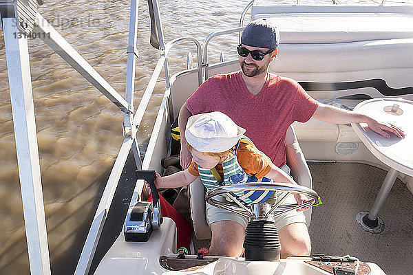 Hochwinkelaufnahme eines Vaters mit Sohn im Boot auf dem See sitzend