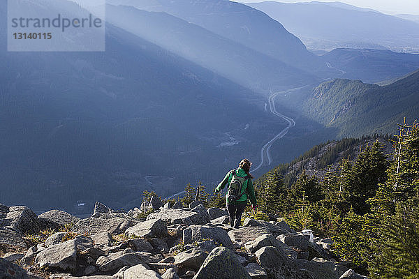 Rückansicht einer Frau  die auf Felsen gegen Berge steht