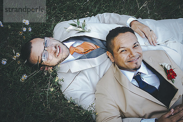 Porträt eines glücklichen homosexuellen Paares auf einem Grasfeld liegend