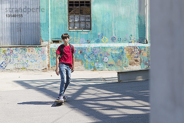 Skateboardfahren in voller Länge für Studenten auf der Straße in der Stadt bei Sonnenschein