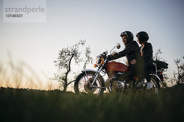 Niedrigwinkelansicht eines jungen Paares auf einem Motorrad bei klarem Himmel