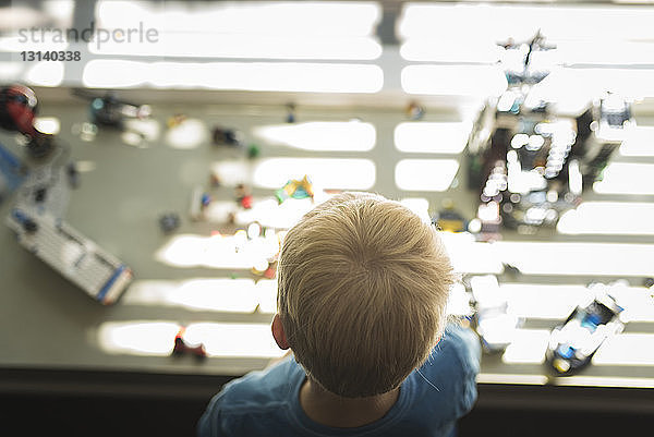 Hochwinkelaufnahme eines Jungen zu Hause mit Spielzeug im Hintergrund