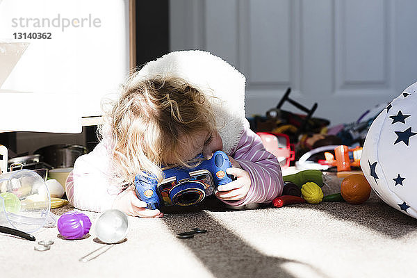 Mädchen spielt zu Hause mit Spielzeug auf dem Teppich