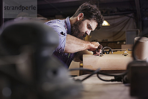 Nahaufnahme eines Arbeiters  der in einer Werkstatt Holzausrüstung herstellt