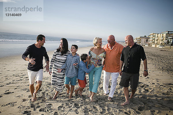 Glückliche Familie geht am Strand gegen den Himmel