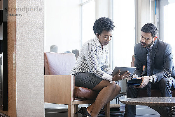 Geschäftsfrau zeigt einem männlichen Kollegen im Büro ein digitales Tablet