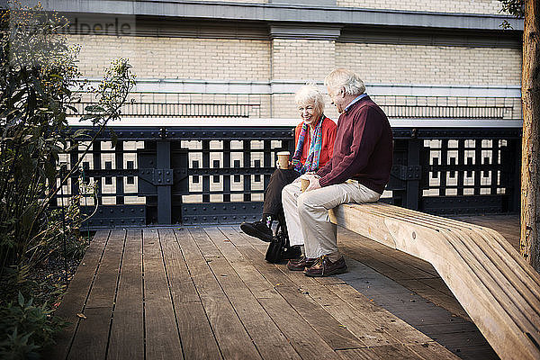 Glückliches älteres Ehepaar sitzt auf einer Holzbank im Innenhof