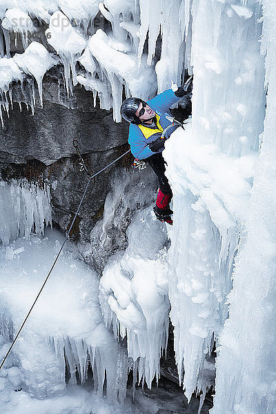 Hochwinkelaufnahme eines Mannes mit Eispickel beim Klettern auf einen Eisberg