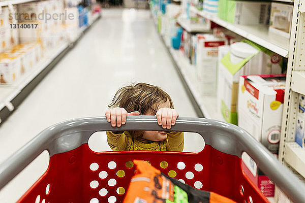 Schrägaufnahme eines Mädchens mit Einkaufswagen  das im Supermarkt steht