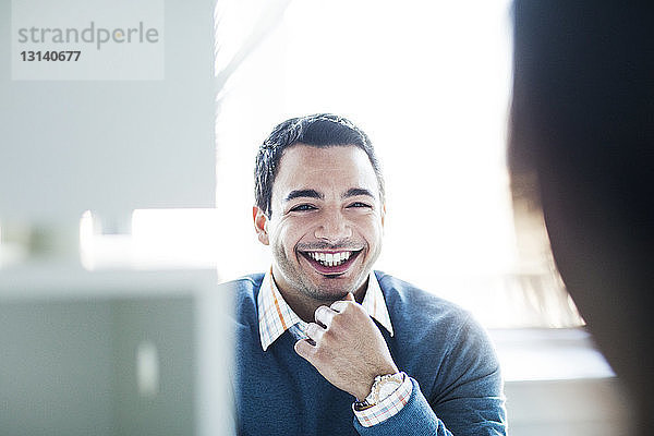 Porträt eines lächelnden Geschäftsmannes  der am Schreibtisch vor dem Fenster sitzt