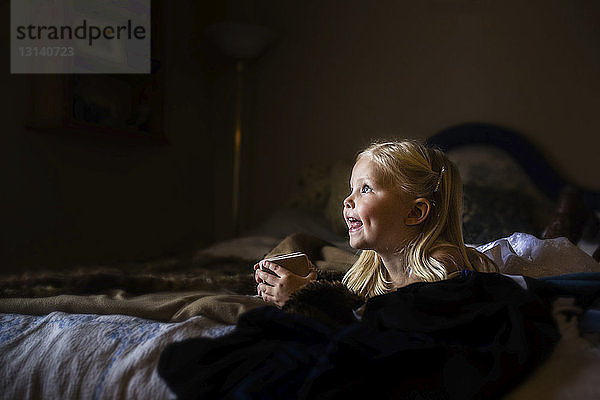 Mädchen hält Kekse  während sie zu Hause auf dem Bett liegt