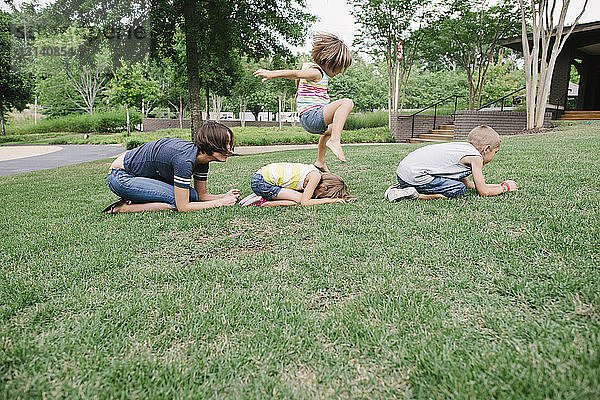 Mutter und Kinder spielen im Park beim Sprung