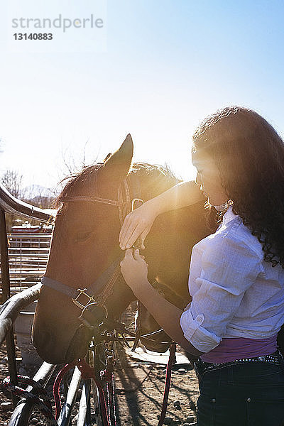 Seitenansicht von Cowgirl mit Pferd vor klarem Himmel stehend