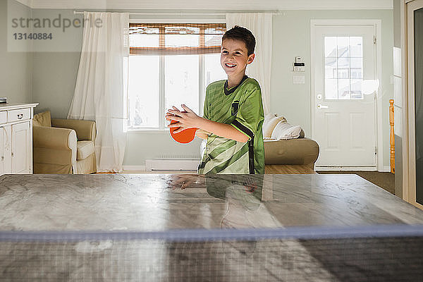 Glücklicher Junge spielt zu Hause Tischtennis
